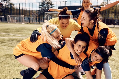 Preview: Women's soccer team celebrating victory at stadium.