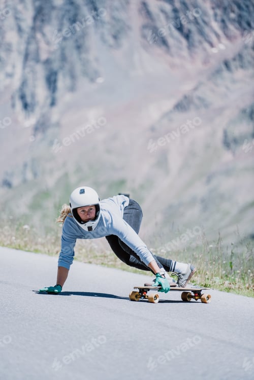 Preview: woman skateboarding and making tricks between the curves on a mountain pass.