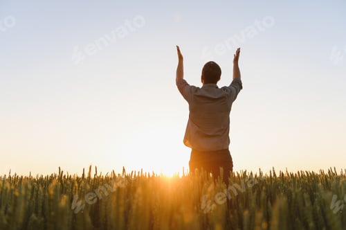 Preview: Sunrise or sunset picture of guy with raised hands looking at sun and enjoying daytime