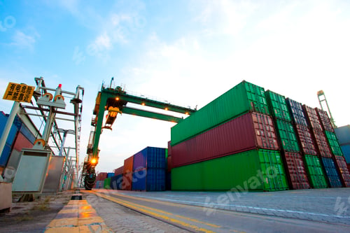Preview: Cranes and multi-colored stack of cargo containers at dusk