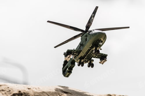 Preview: toy helicopter flying high in clear sky above sand