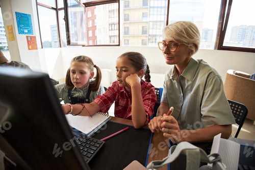 Preview: Caucasian Female Teacher Guiding Two Preteen Girls Using Computer in Classroom