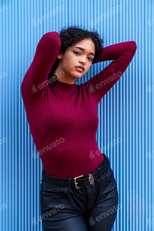 Preview: Beautiful Young Brunette Caucasian Model Posing Against a Vibrant Blue Wall in a Colorful Photoshoot