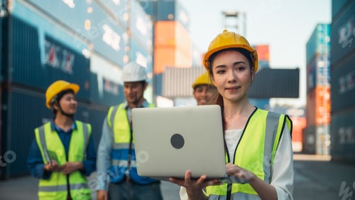 Preview: Female worker laptop shipping container safety vest hard hat logistics team focus work cargo yard