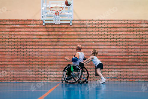 Preview: Disabled sport men and little girl in action while playing indoor basketball