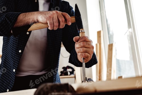 Preview: Hands of a carpenter working with chisel and hammer