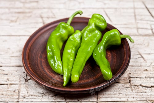 Preview: Fresh green raw peppers on brown ceramic plate on rustic wooden table background.