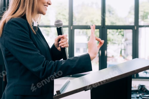 Preview: cropped image of lecturer showing okay gesture at podium tribune during seminar in conference hall