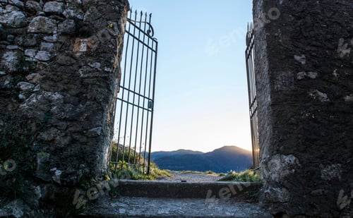 Preview: Stone walls and old open gates with distant view of mountains at sunset