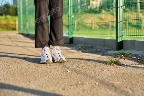 Preview: Close-up of legs in white sneakers at the stadium, copy space road