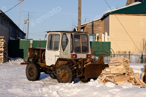Preview: An old small tractor and a pile of chopped firewood at a house in the village