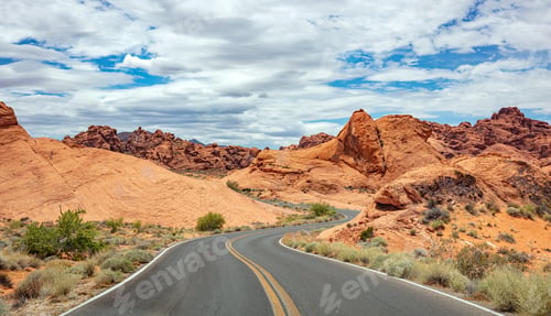 Preview: Long winding highway with ups and downs, cloudy blue sky. Valley of Fire Nevada, USA