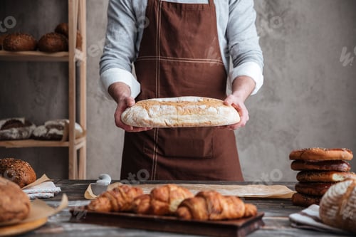 Preview: Cropped photo of young man baker holding bread.