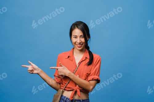 Preview: Asian lady smiling with cheerful expression, shows something amazing at blank space.