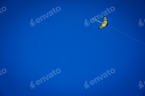 Preview: Colorful kite flying in the blue sky, negative space for copy.