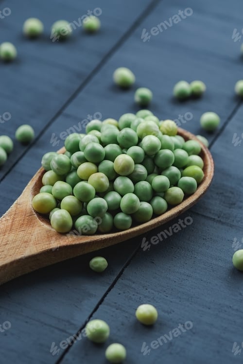 Preview: Diagonal composition of some peas on a wooden spoon on a black table