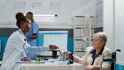 Preview: African american physician giving prescription paper to senior patient