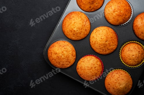Preview: Appetizing orange muffins or cupcakes on black table background, winter homemade pastries, top view