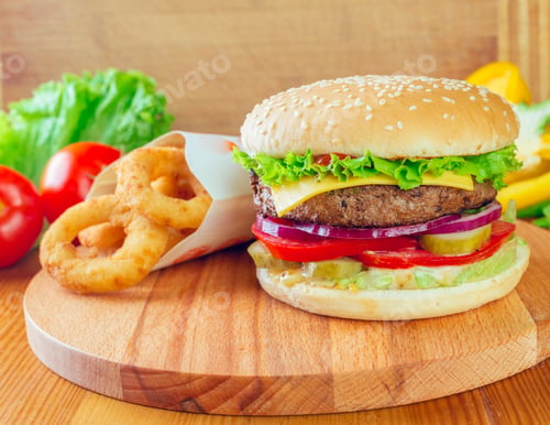 Preview: Delicious cheeseburger served with crispy onion rings and fresh vegetables on a wooden board