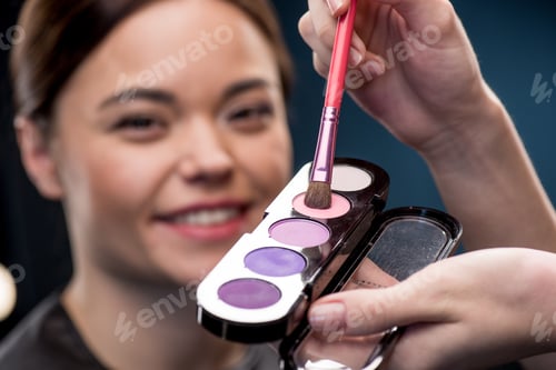 Preview: Close-up partial view of make-up artist picking up color of eyeshadow palette