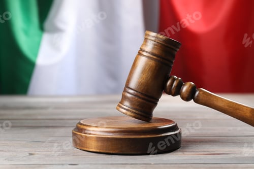 Preview: Judge's gavel on wooden table against flag of Italy, closeup