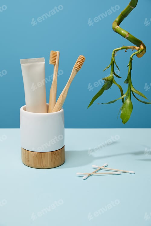 Preview: holder with bamboo toothbrushes, toothpaste in tube, ear sticks and bamboo stem on table and blue
