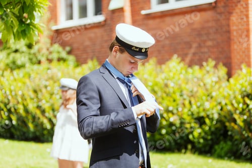 Preview: Male university student adjusting necktie at graduation party