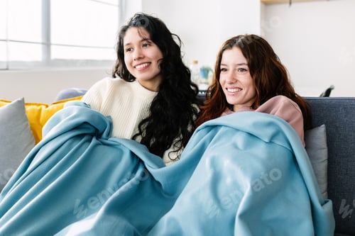 Preview: Happy young millennial people relaxing on sofa watching TV together on winter