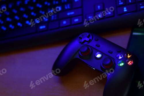 Preview: Modern gamepad lies with keyboard on table in dark playroom scene close up