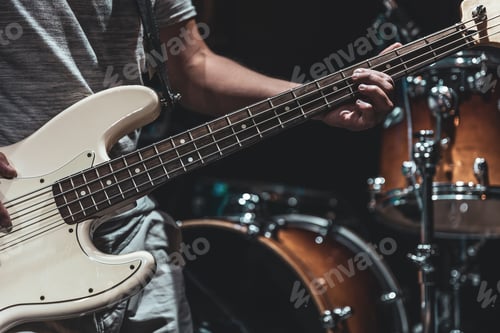 Preview: A man plays the bass guitar on a blurred background with bokeh.