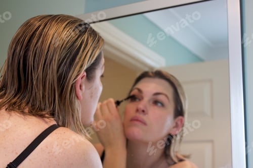 Preview: woman applying mascara in mirror