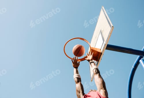 Preview: Young male basketball player throwing ball in basketball hoop