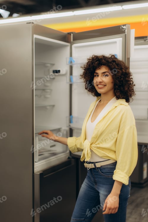 Preview: Smiling Woman Examining Modern Refrigerator in Appliance Store