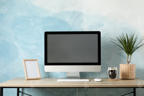 Preview: Workplace with computer, plant and glass of coffee on wooden table. Light blue background