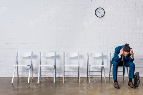 Preview: Stressed businessman sitting on chair and waiting for interview