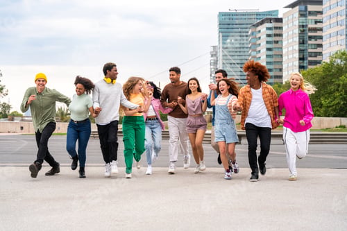 Preview: Happy playful multiethnic group of young friends bonding outdoors
