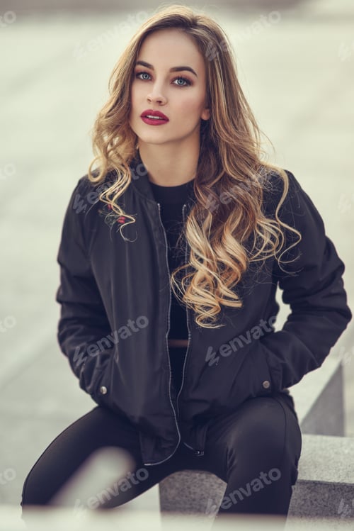 Preview: Beautiful young girl wearing black jacket sitting in the street.