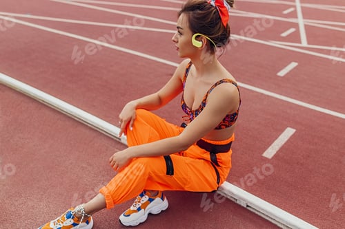 Preview: Trendy sportswoman listening to music on track