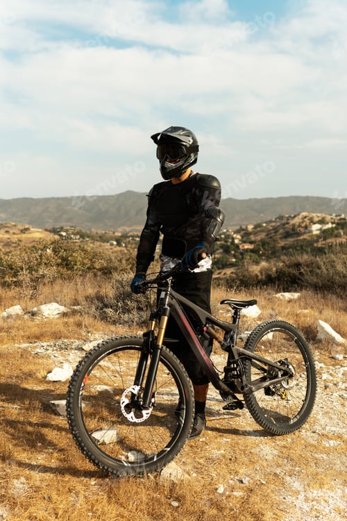 Preview: Downhill rider fully equipped with protective gear and his bicycle