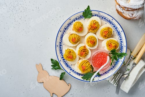 Preview: Stuffed eggs with red caviar and paprika on plate for appetizer easter table, top view, copy space.