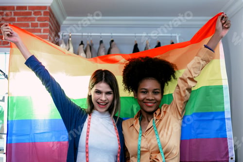 Preview: Happy women standing with a pride rainbow flag.