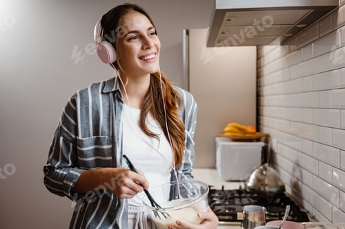 Preview: Pleased beautiful woman smiling and making pancakes dough