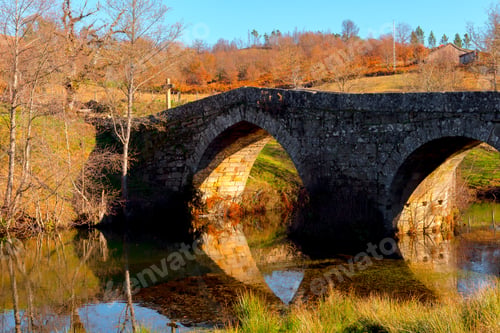 Preview: Old bridge over calm river in autumn countryside