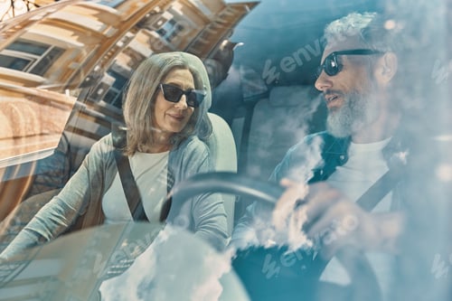 Preview: Happy senior couple enjoying car ride while sitting on front seats of the car