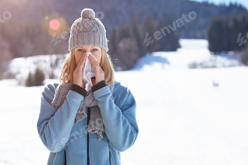 Preview: Woman blowing her nose on a cold winter's day outdoors