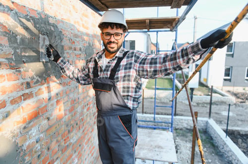 Preview: Construction worker plastering brick wall on scaffolding