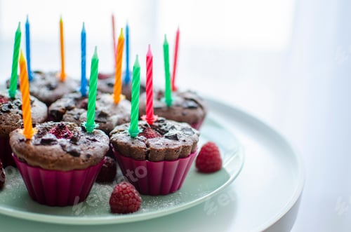 Festive Cupcakes with Raspberry Topping and Colorful Candles