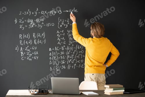 Preview: Rear view of contemporary teacher in casualwear writing formulas on blackboard