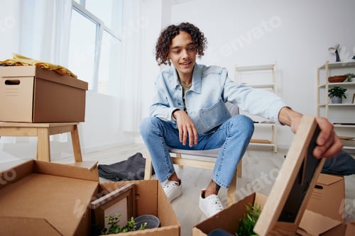 Preview: A young man sitting on a chair with boxes moving Lifestyle