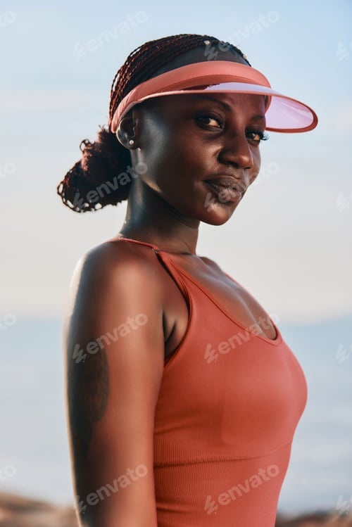 Preview: Confident woman in a coral tank top and visor against a serene outdoor background
